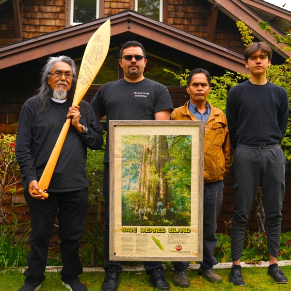 Image gallery pop-up of four individuals standing for a photo. One person is holding a carving and another person is holding a framed poster.