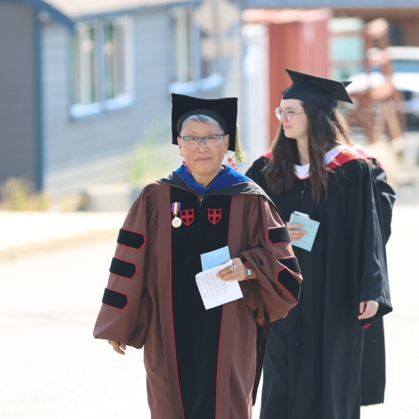 Dr. Imogene Lim, Convocation Marshall, leading students to gymnasium, with Zoe, Anthropology Honours graduand.  June 22, 2023.
