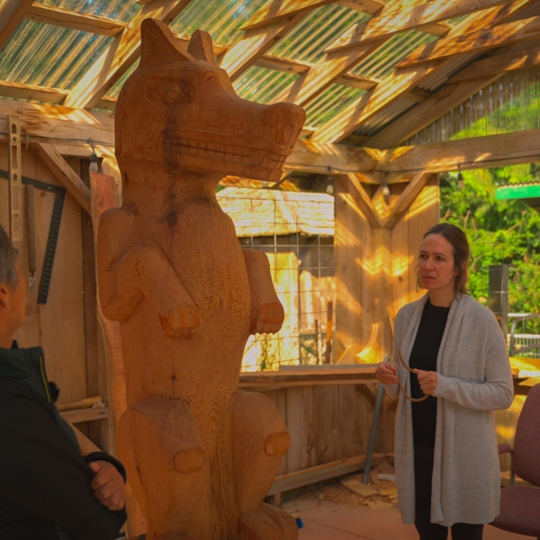 Image gallery pop-up of two individuals standing inside a workshop and looking at a tall wooden carving.