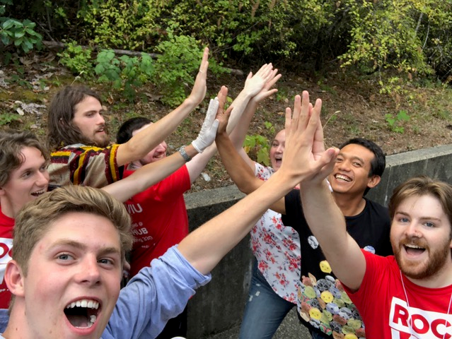 A group of students outside hi-fiving each other with big smiles 