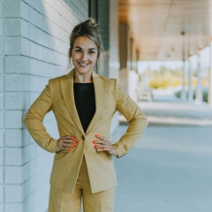 A smiling young woman in a pantsuit. 